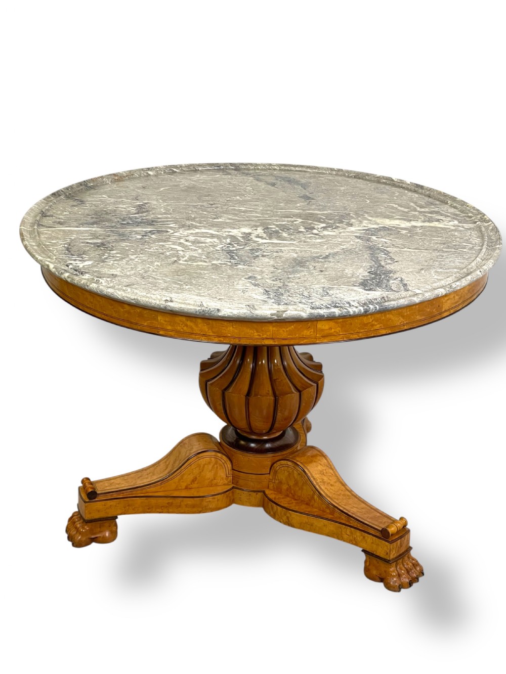 A circular antique French Empire gueridon table featuring a grey-veined marble top on a carved wooden pedestal with a triform base and lion paw feet.
