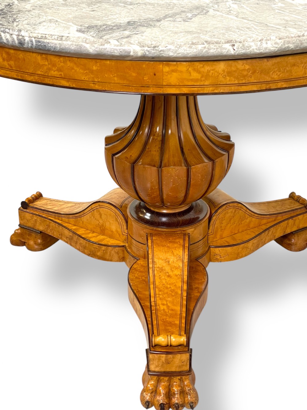 A circular antique French Empire gueridon table featuring a grey-veined marble top on a carved wooden pedestal with a triform base and lion paw feet. View IV