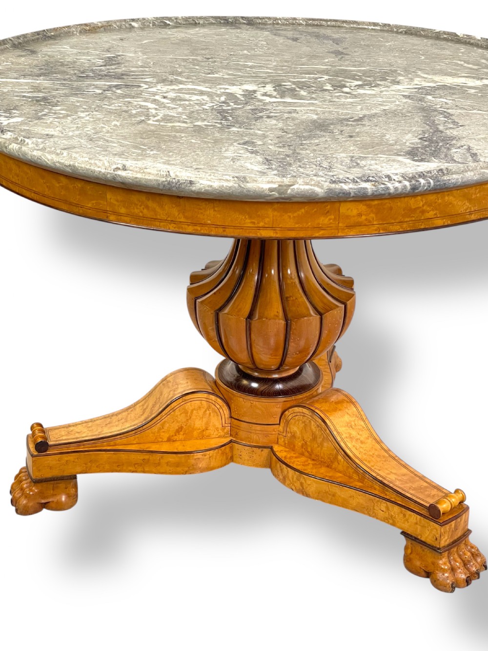 A circular antique French Empire gueridon table featuring a grey-veined marble top on a carved wooden pedestal with a triform base and lion paw feet. View V