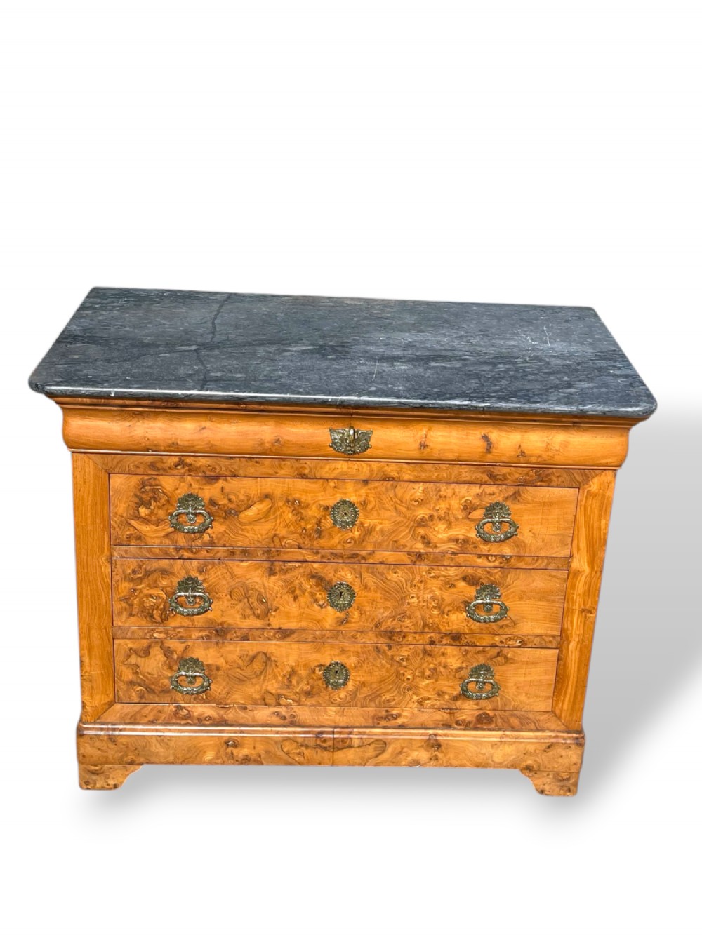 A French Louis Philippe style burr ash commode featuring a dark grey marble top, four drawers, and ornate brass handles. View II