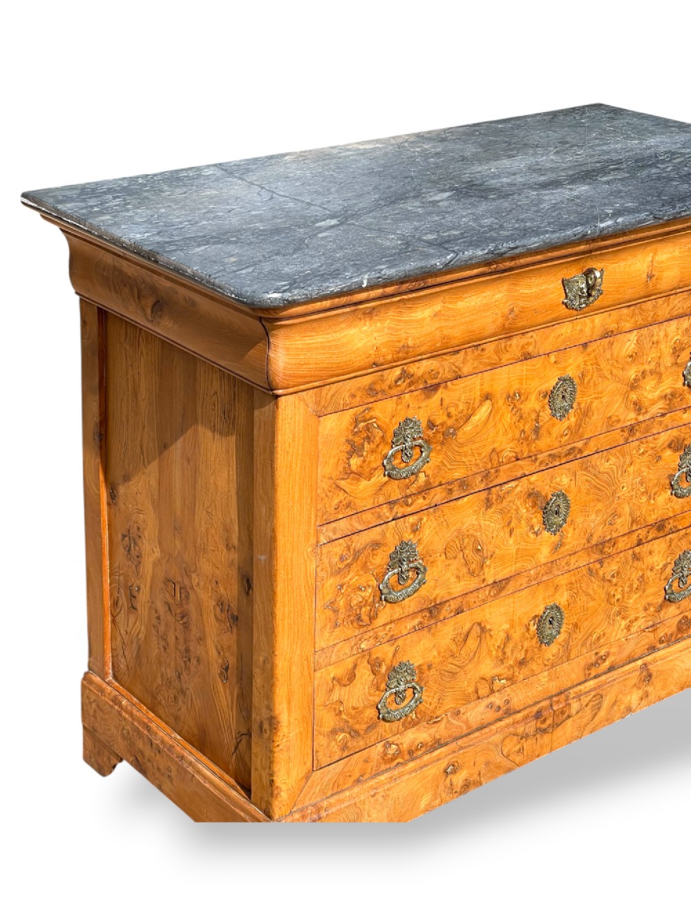 A French Louis Philippe style burr ash commode featuring a dark grey marble top, four drawers, and ornate brass handles. View IV