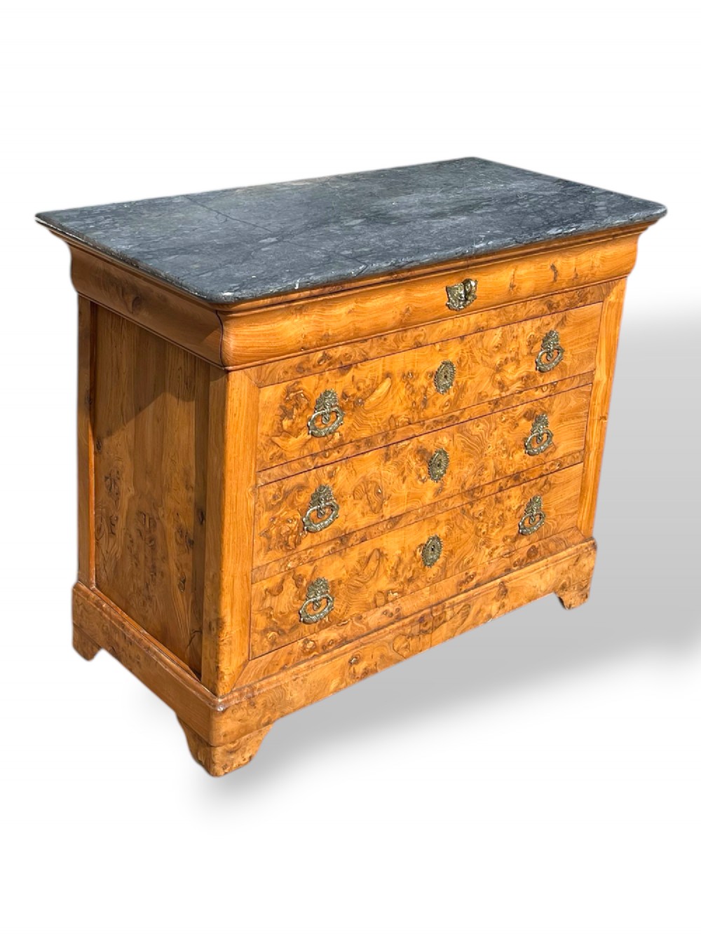A French Louis Philippe style burr ash commode featuring a dark grey marble top, four drawers, and ornate brass handles. View V