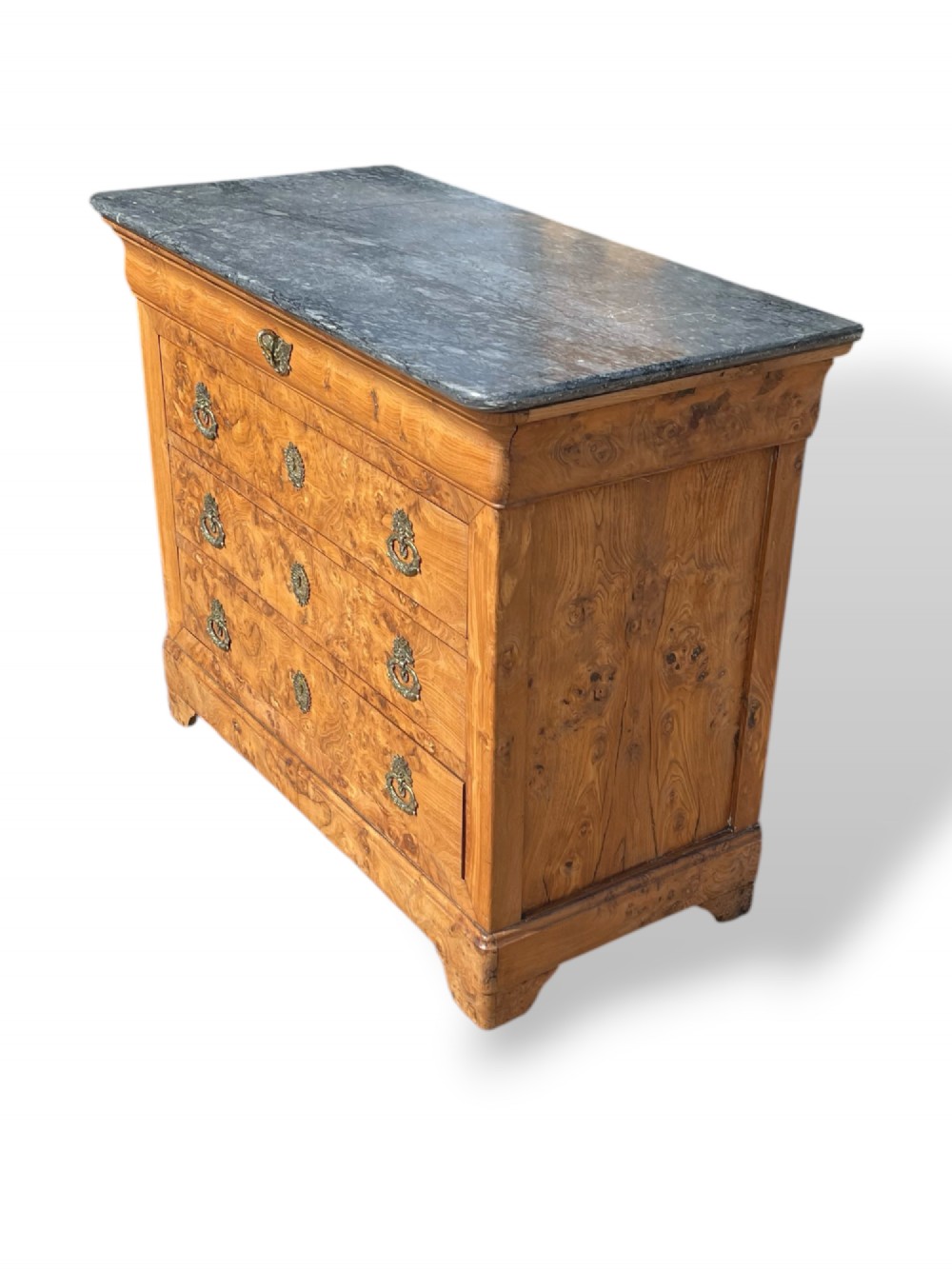 A French Louis Philippe style burr ash commode featuring a dark grey marble top, four drawers, and ornate brass handles. View VI