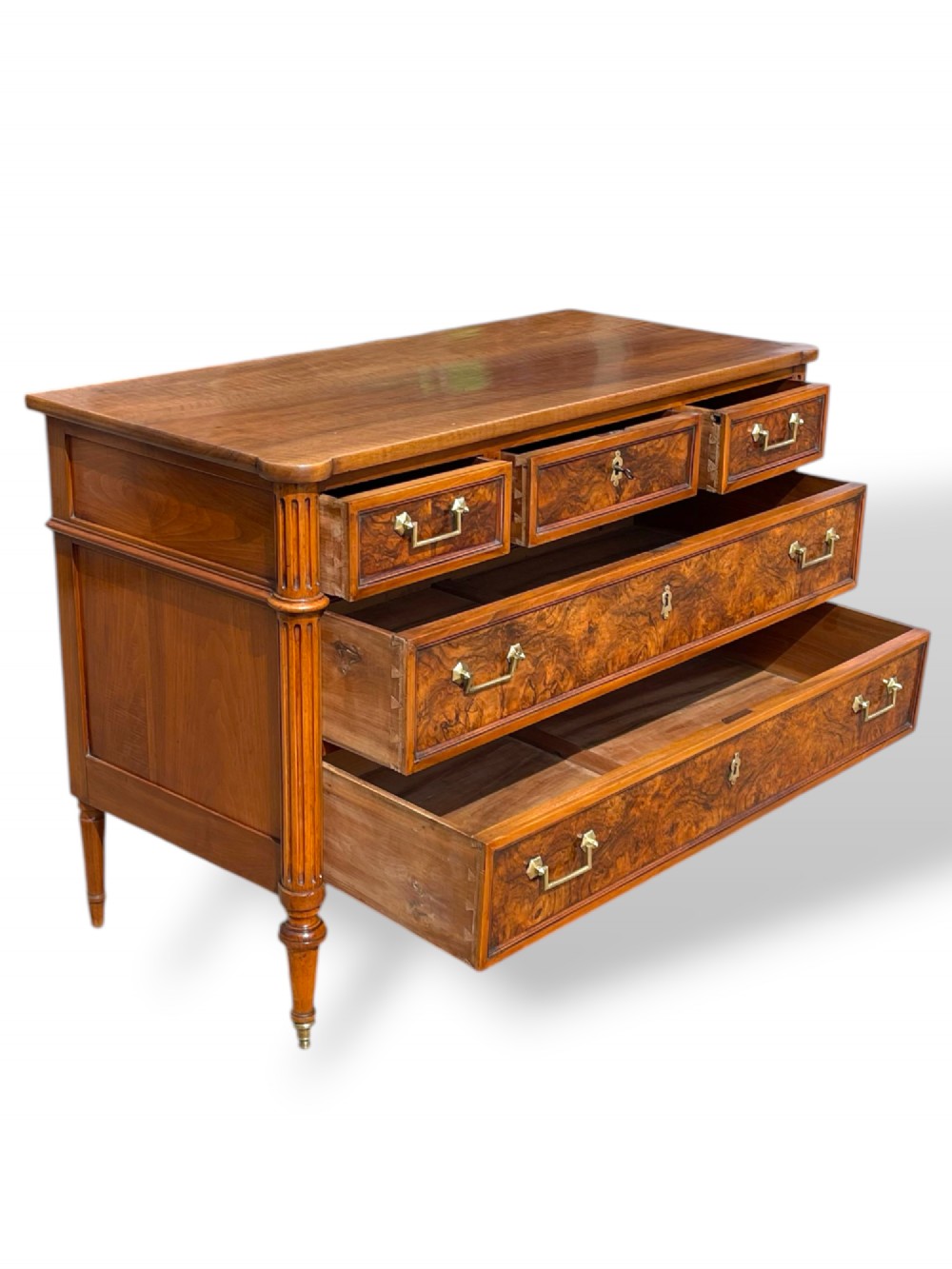 An eighteenth-century French walnut commode featuring figure-grained drawer fronts, brass handles, fluted corner pilasters, and tapered turned legs. View II