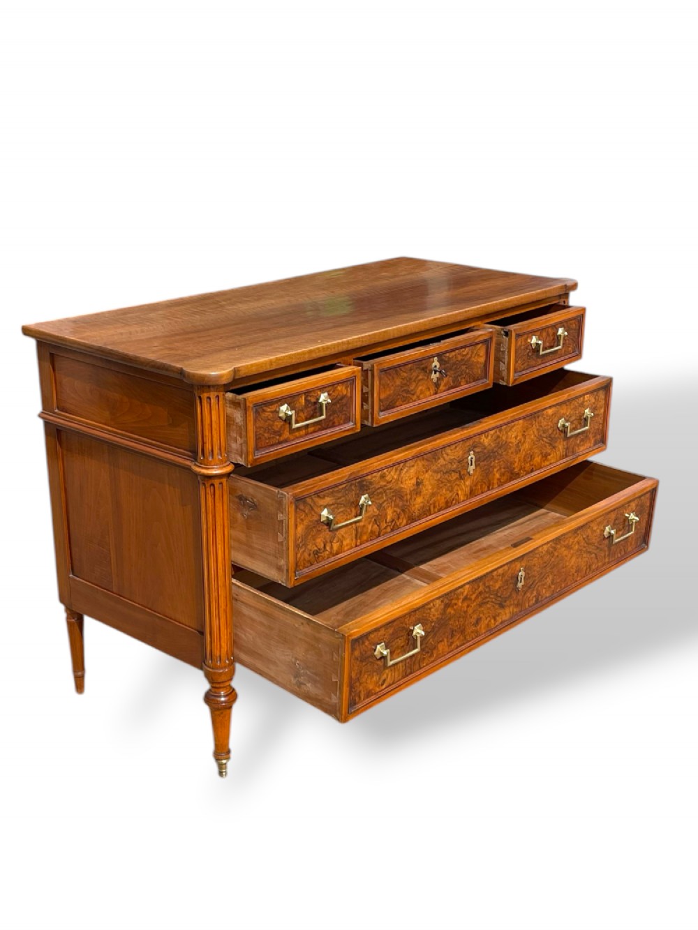 An eighteenth-century French walnut commode featuring figure-grained drawer fronts, brass handles, fluted corner pilasters, and tapered turned legs. View III