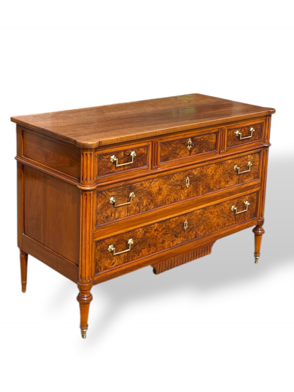 An eighteenth-century French walnut commode featuring figure-grained drawer fronts, brass handles, fluted corner pilasters, and tapered turned legs. View IV