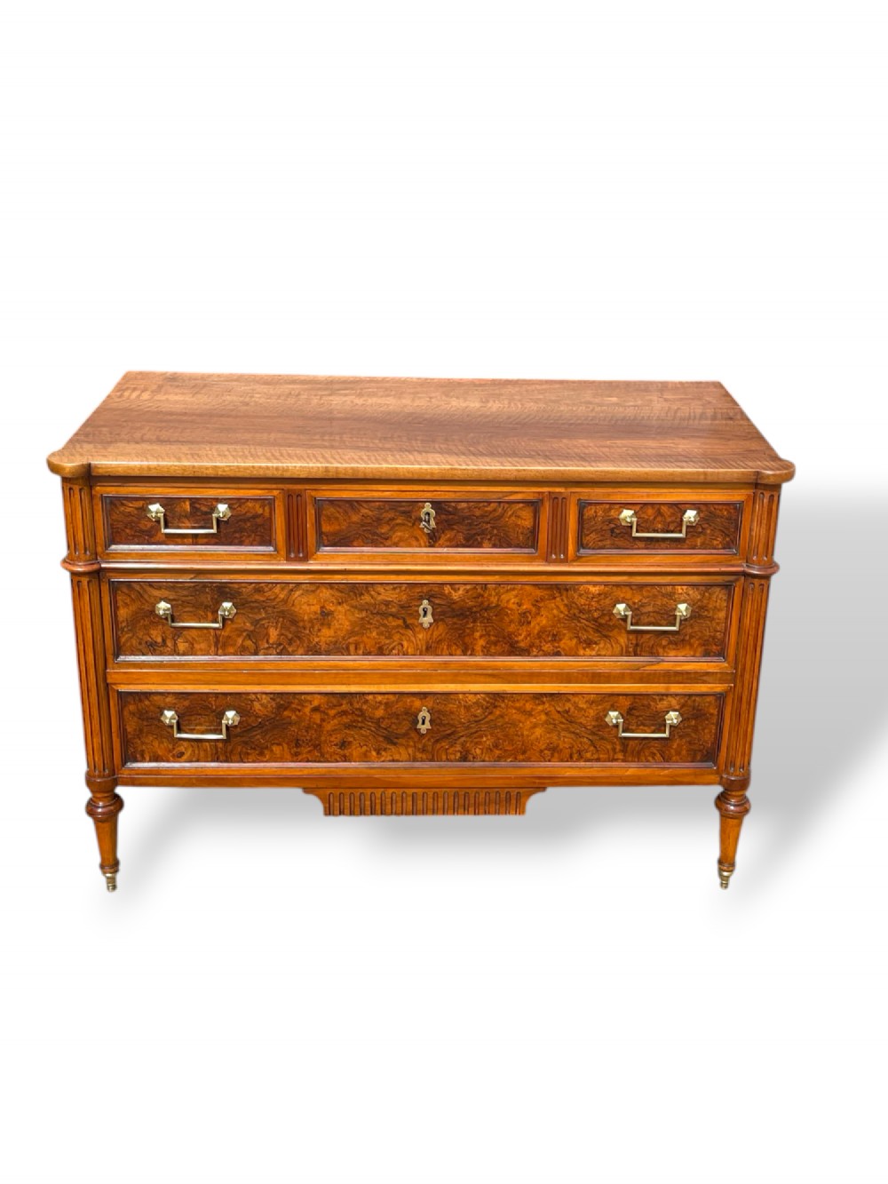 An eighteenth-century French walnut commode featuring figure-grained drawer fronts, brass handles, fluted corner pilasters, and tapered turned legs. View VIII