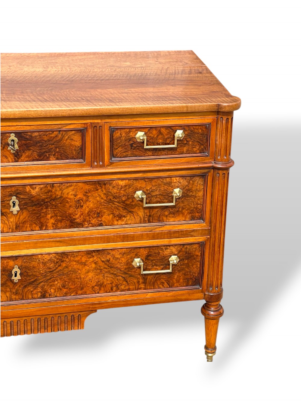 An eighteenth-century French walnut commode featuring figure-grained drawer fronts, brass handles, fluted corner pilasters, and tapered turned legs. View XII