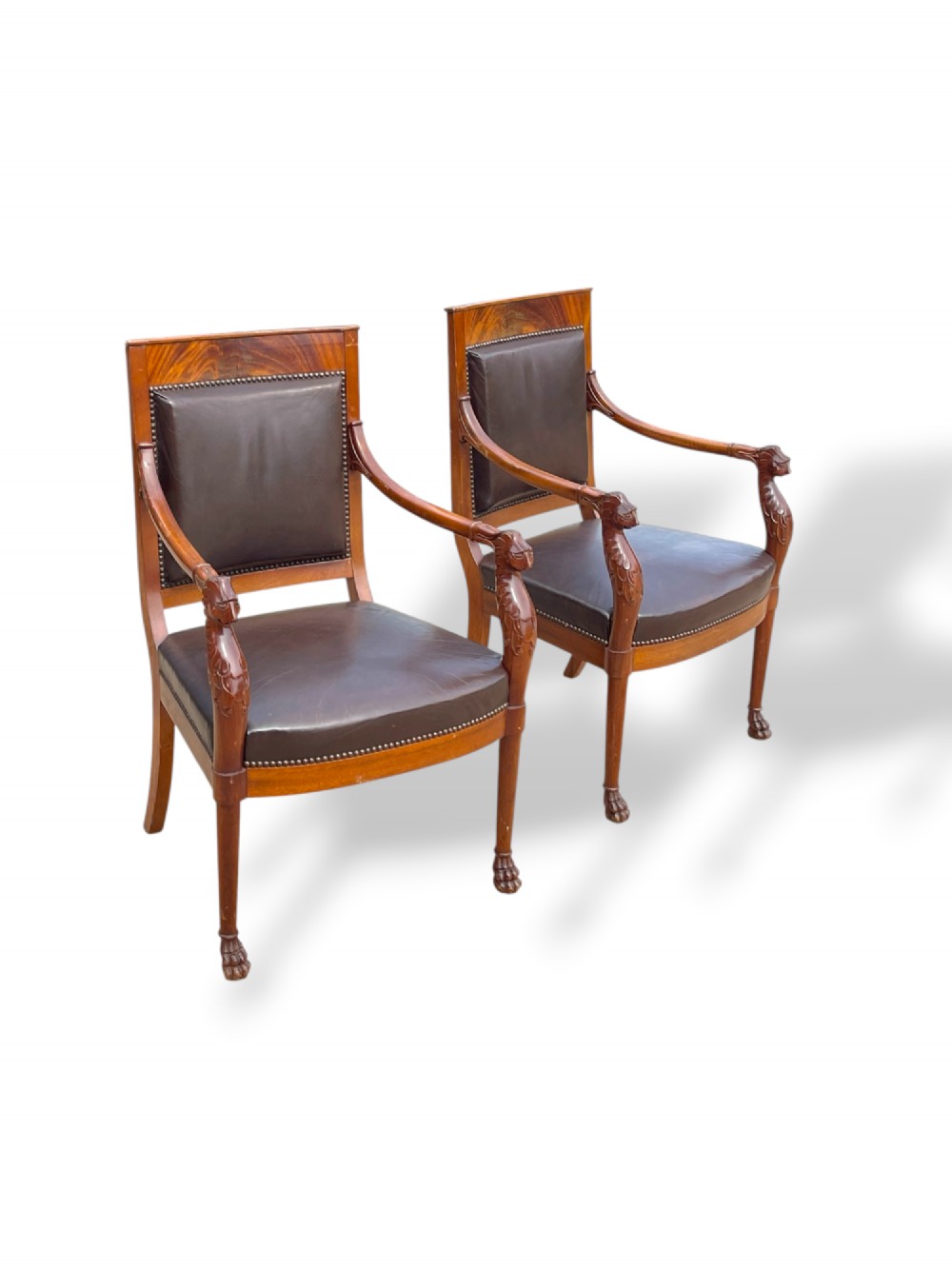 A pair of twentieth-century French Empire style armchairs featuring carved mahogany frames, dark brown leather upholstery, and brass stud trim. View II