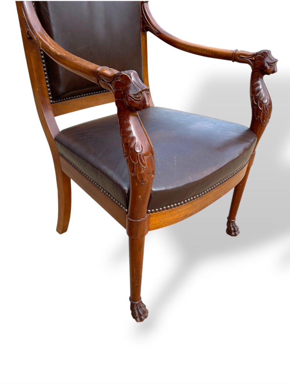 A pair of twentieth-century French Empire style armchairs featuring carved mahogany frames, dark brown leather upholstery, and brass stud trim. View IV