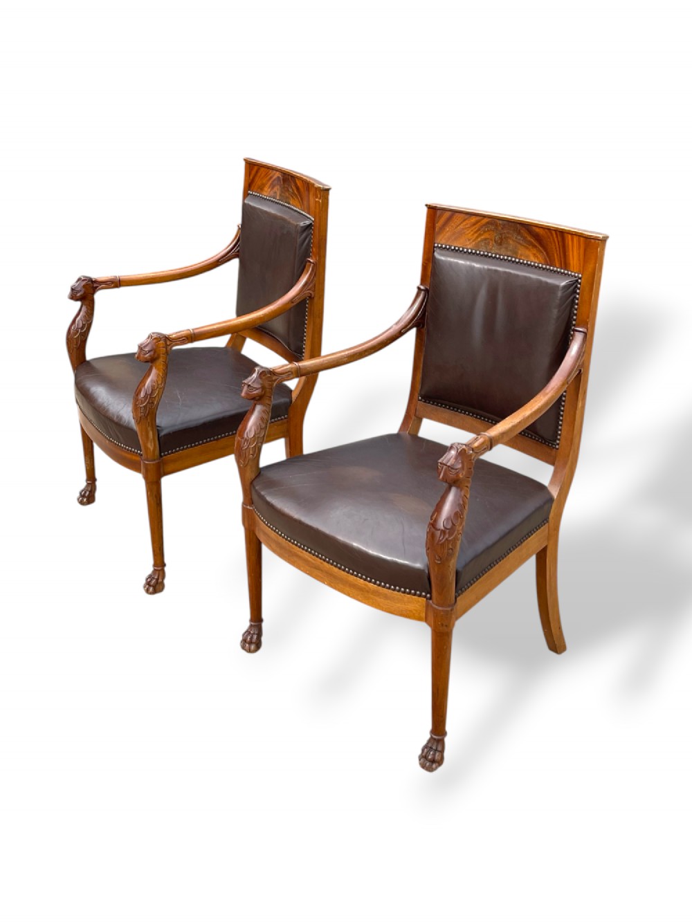 A pair of twentieth-century French Empire style armchairs featuring carved mahogany frames, dark brown leather upholstery, and brass stud trim. View VI