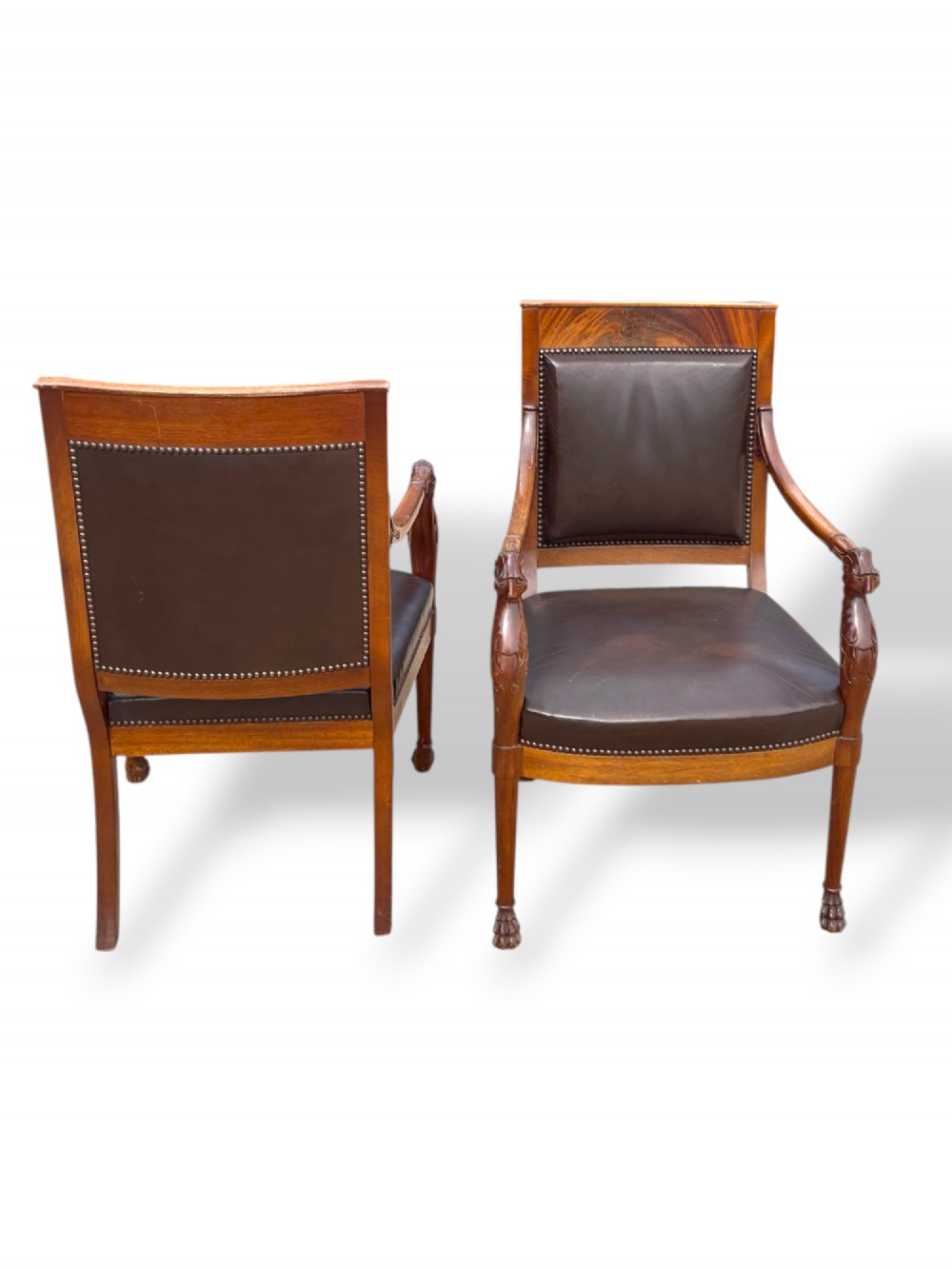 A pair of twentieth-century French Empire style armchairs featuring carved mahogany frames, dark brown leather upholstery, and brass stud trim. View IX