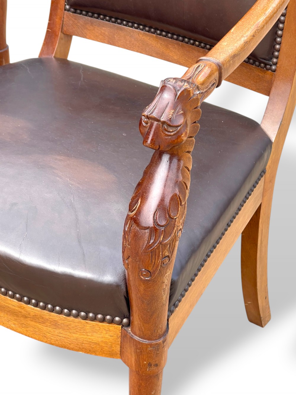 A pair of twentieth-century French Empire style armchairs featuring carved mahogany frames, dark brown leather upholstery, and brass stud trim. View XII