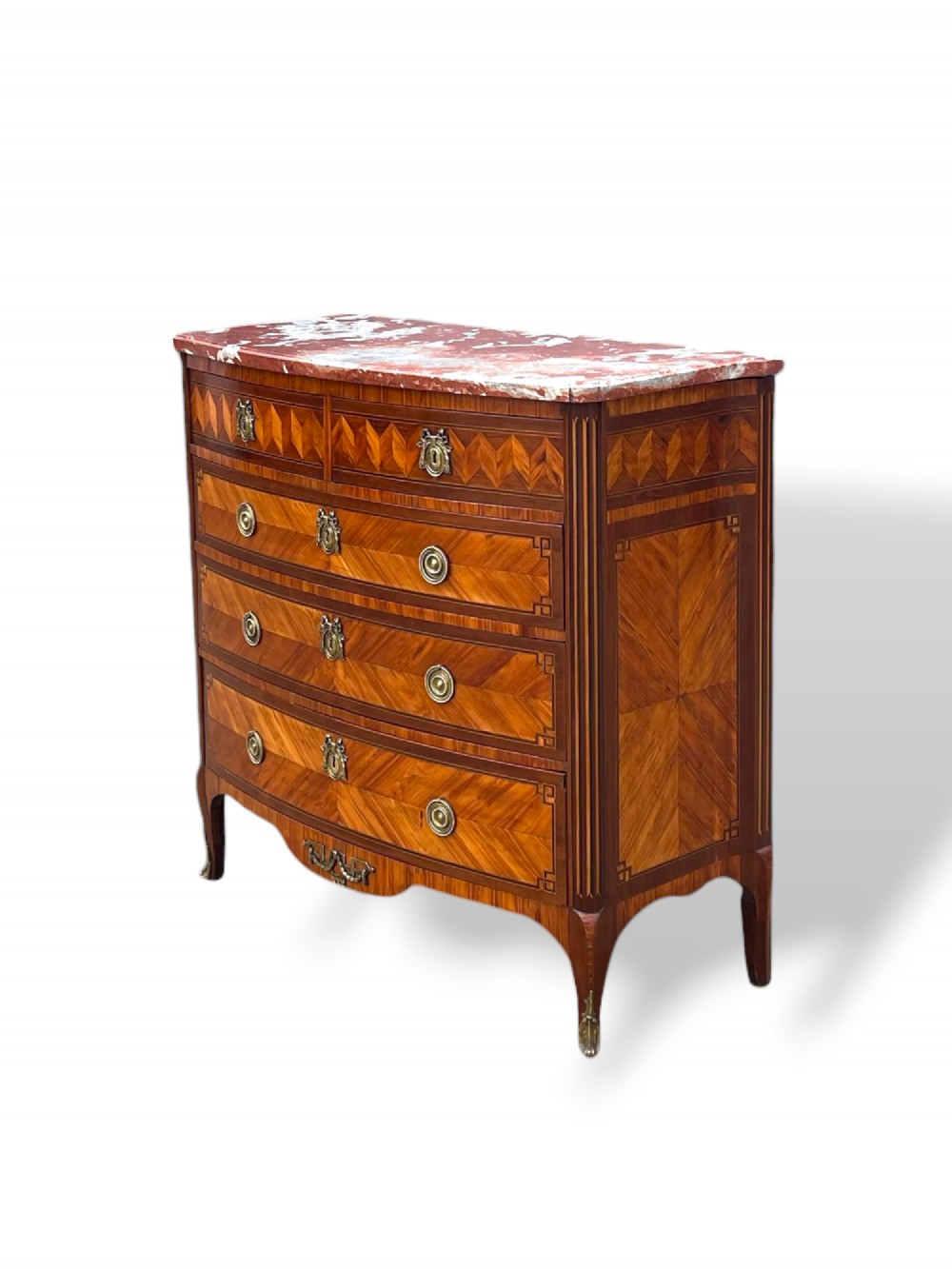 A 19th-century French wooden commode featuring chevron parquetry veneer, decorative brass handles, keyhole mounts, and a variegated reddish-pink marble top. View II
