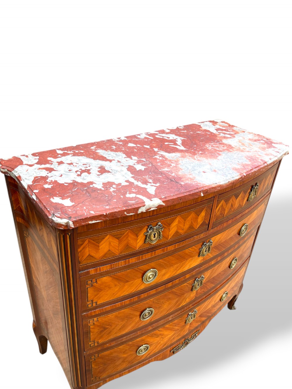 A 19th-century French wooden commode featuring chevron parquetry veneer, decorative brass handles, keyhole mounts, and a variegated reddish-pink marble top. View III