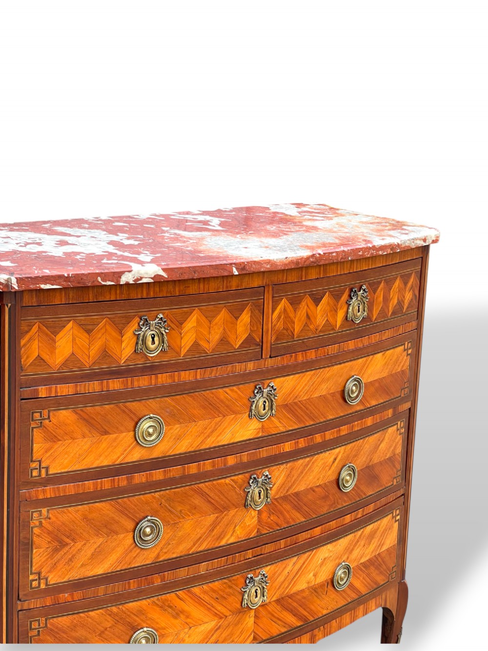 A 19th-century French wooden commode featuring chevron parquetry veneer, decorative brass handles, keyhole mounts, and a variegated reddish-pink marble top. View IV