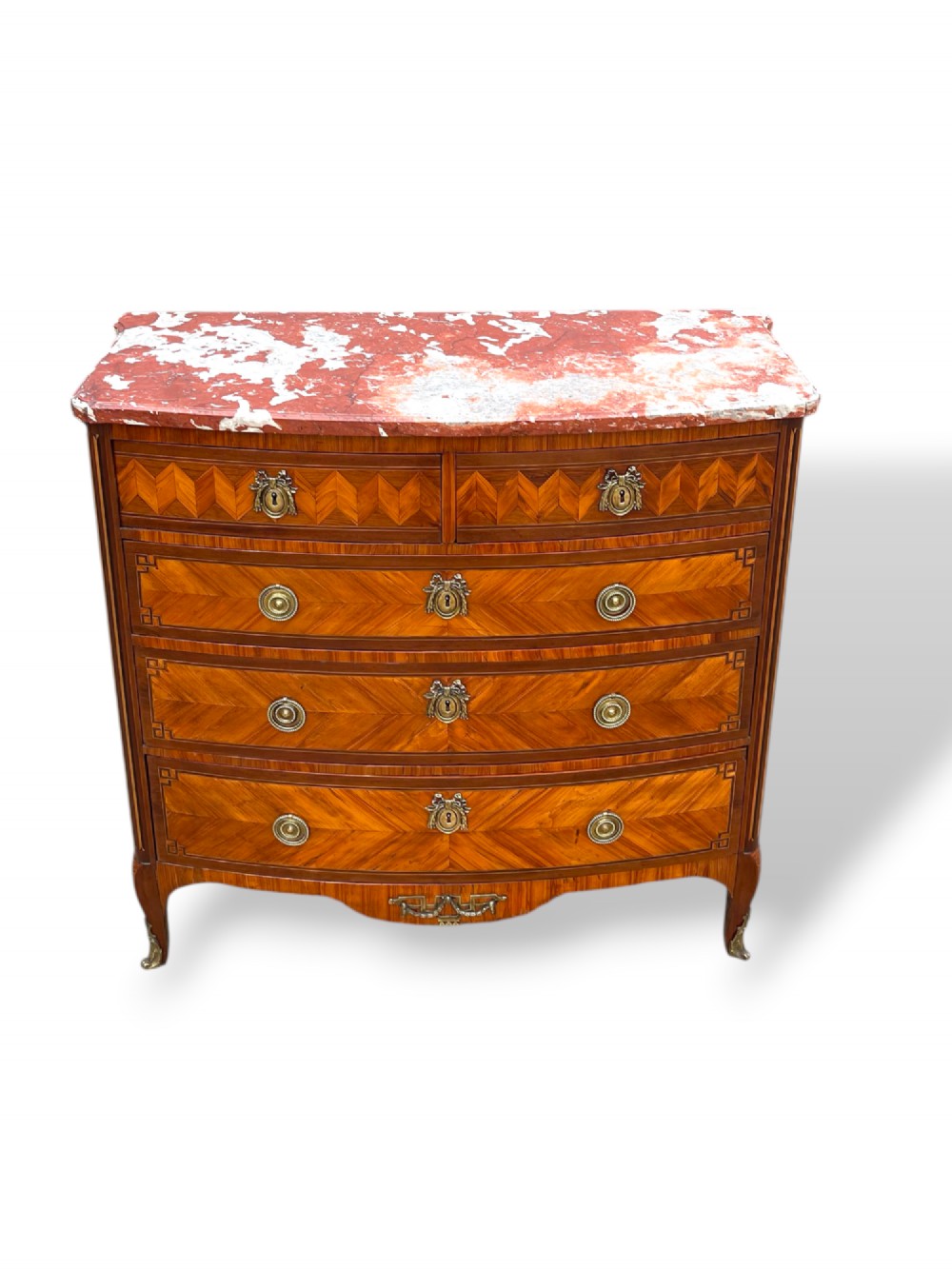 A 19th-century French wooden commode featuring chevron parquetry veneer, decorative brass handles, keyhole mounts, and a variegated reddish-pink marble top. View VIII