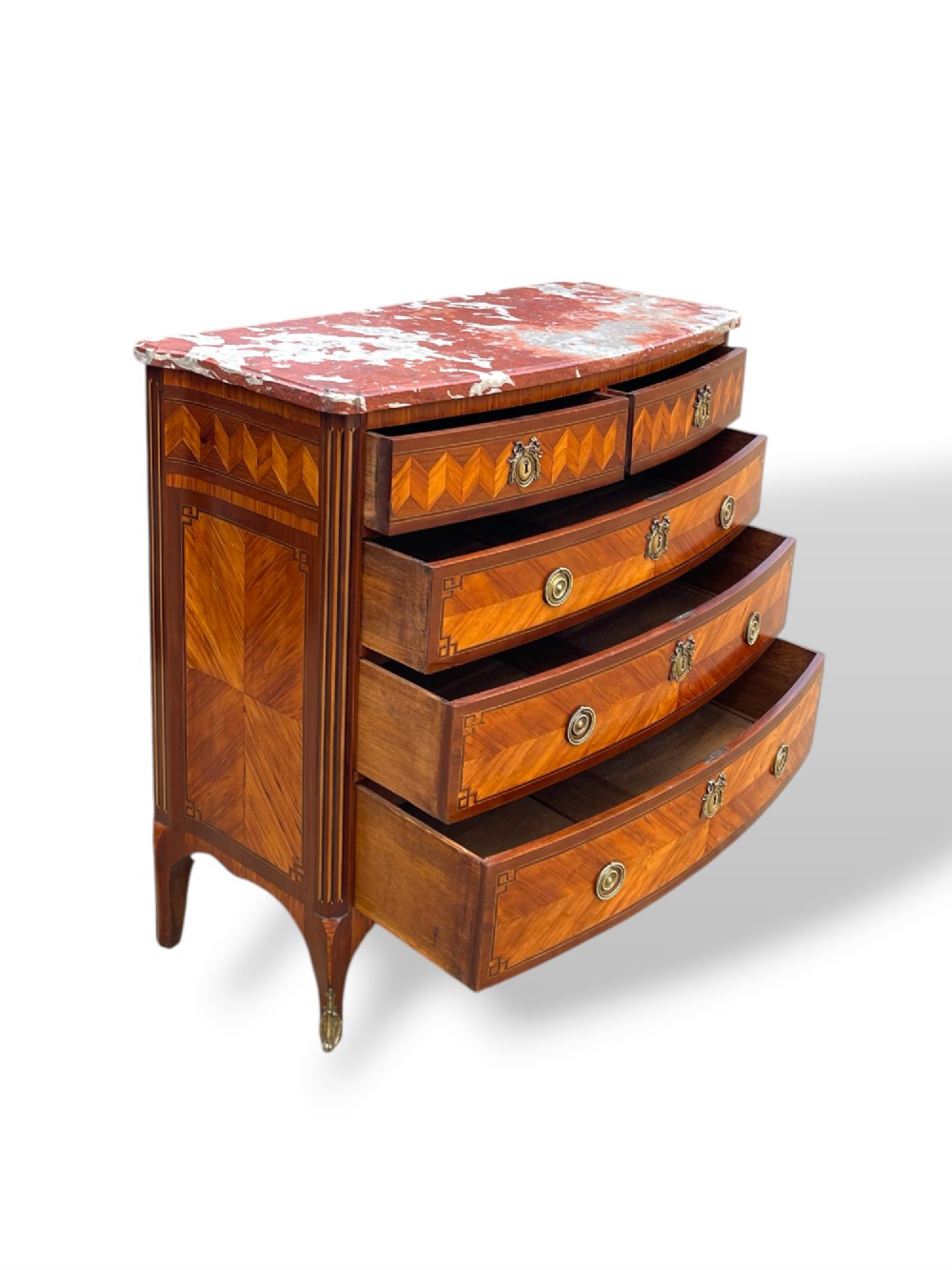 A 19th-century French wooden commode featuring chevron parquetry veneer, decorative brass handles, keyhole mounts, and a variegated reddish-pink marble top. View IX