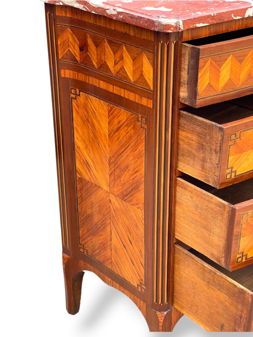 A 19th-century French wooden commode featuring chevron parquetry veneer, decorative brass handles, keyhole mounts, and a variegated reddish-pink marble top. View XII