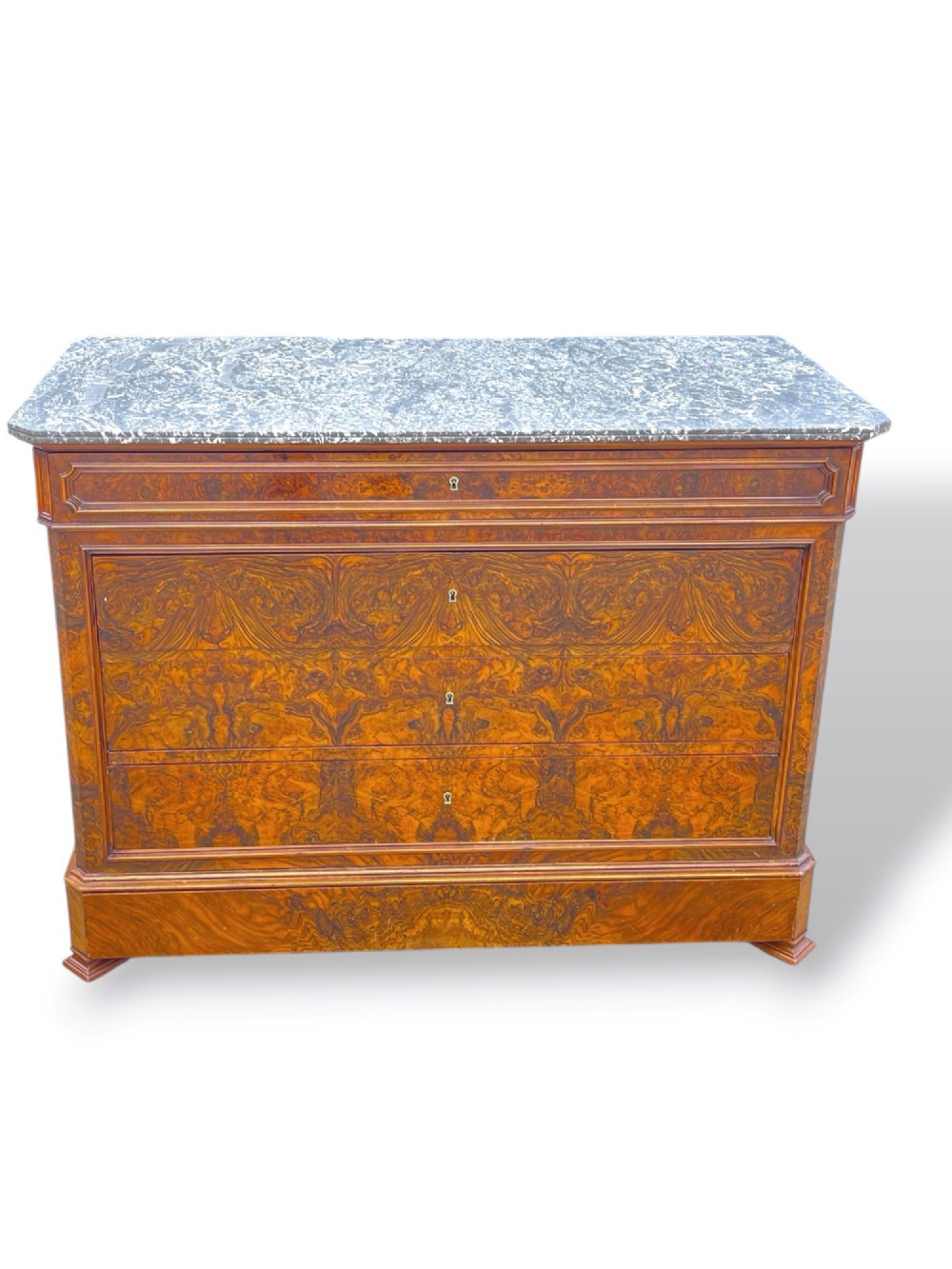 A 19th-century French Louis Philippe walnut commode featuring a grey marble top surface and figured walnut timber drawers with brass keyhole escutcheons.