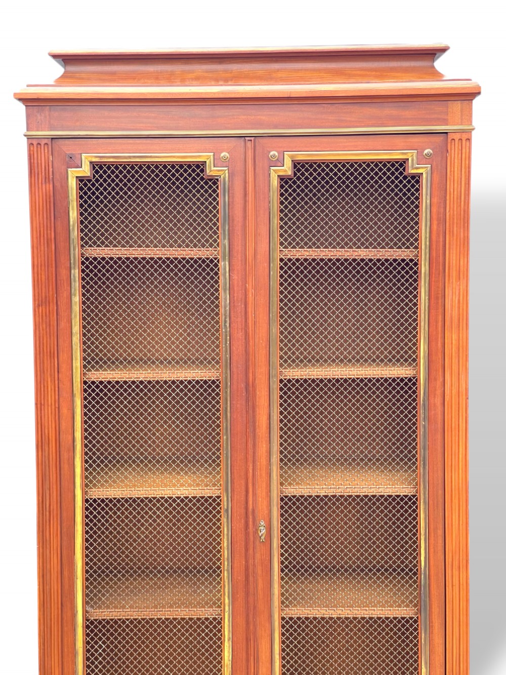 A tall French Empire style mahogany two-door bookcase featuring brass wire mesh door panels and fluted side columns. View II