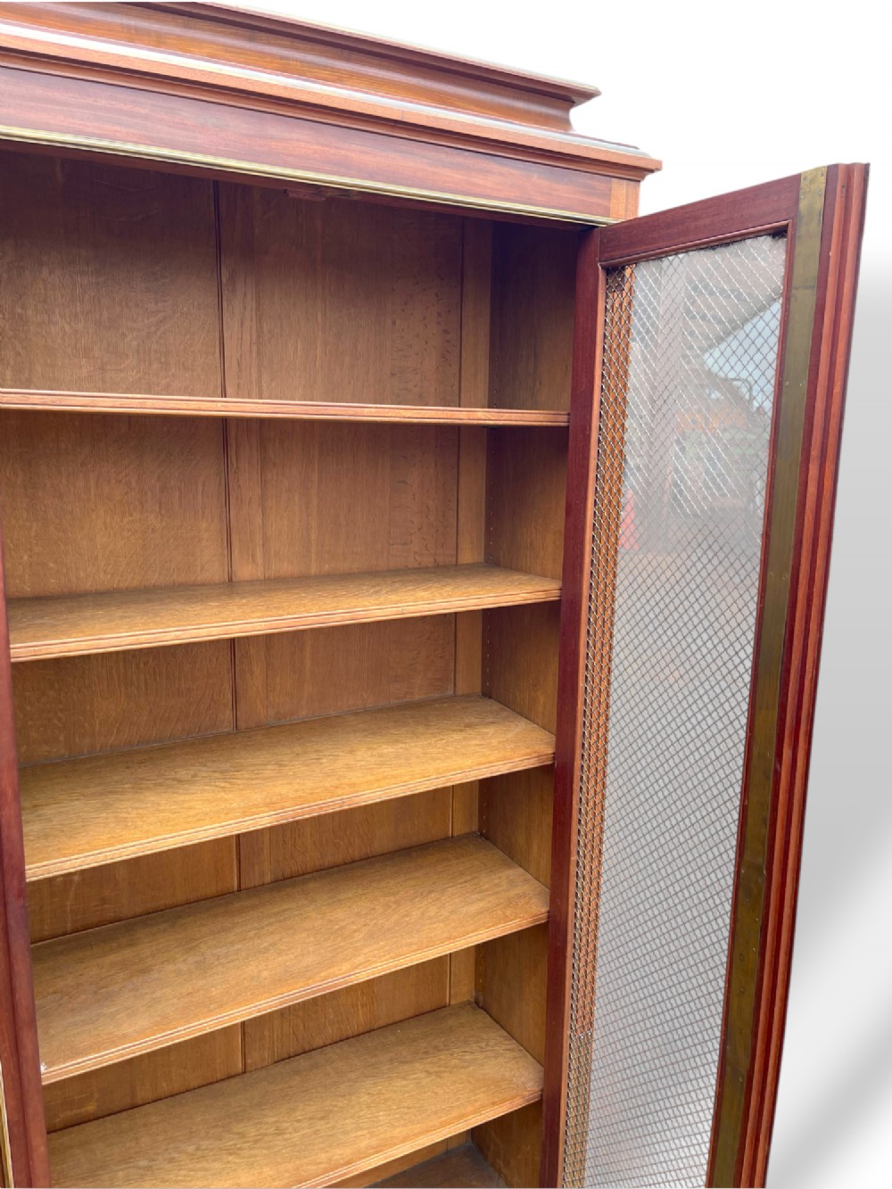 A tall French Empire style mahogany two-door bookcase featuring brass wire mesh door panels and fluted side columns. View III