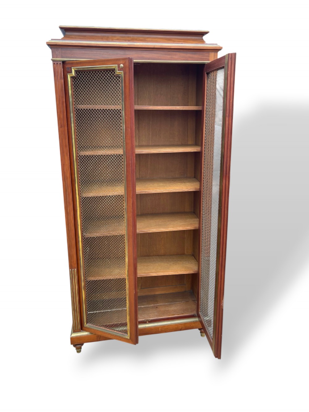 A tall French Empire style mahogany two-door bookcase featuring brass wire mesh door panels and fluted side columns. View IV