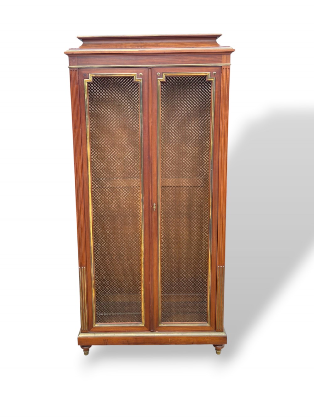 A tall French Empire style mahogany two-door bookcase featuring brass wire mesh door panels and fluted side columns. View VI