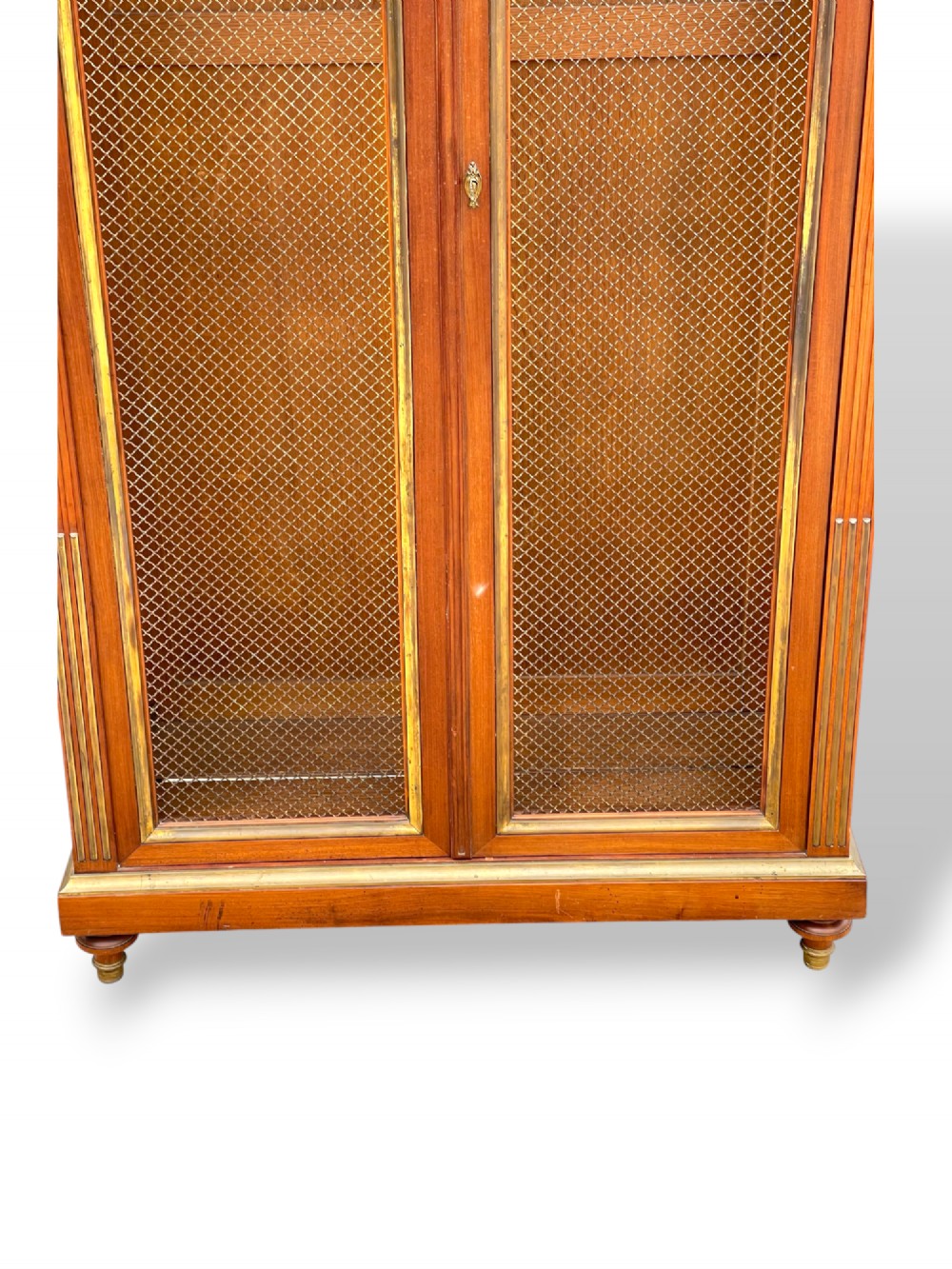 A tall French Empire style mahogany two-door bookcase featuring brass wire mesh door panels and fluted side columns. View VII