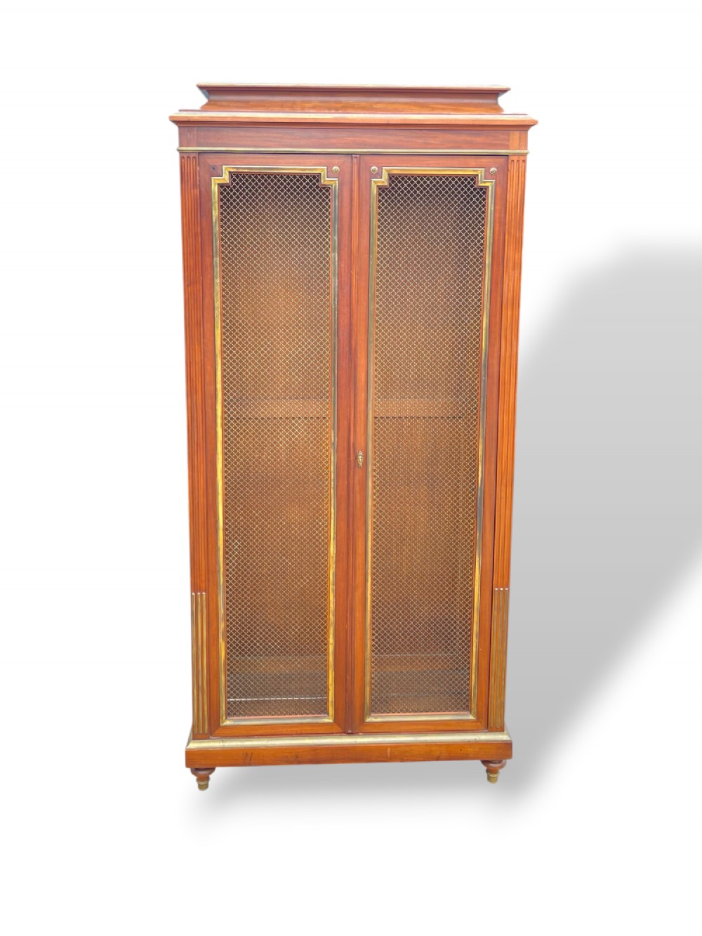 A tall French Empire style mahogany two-door bookcase featuring brass wire mesh door panels and fluted side columns. View VIII