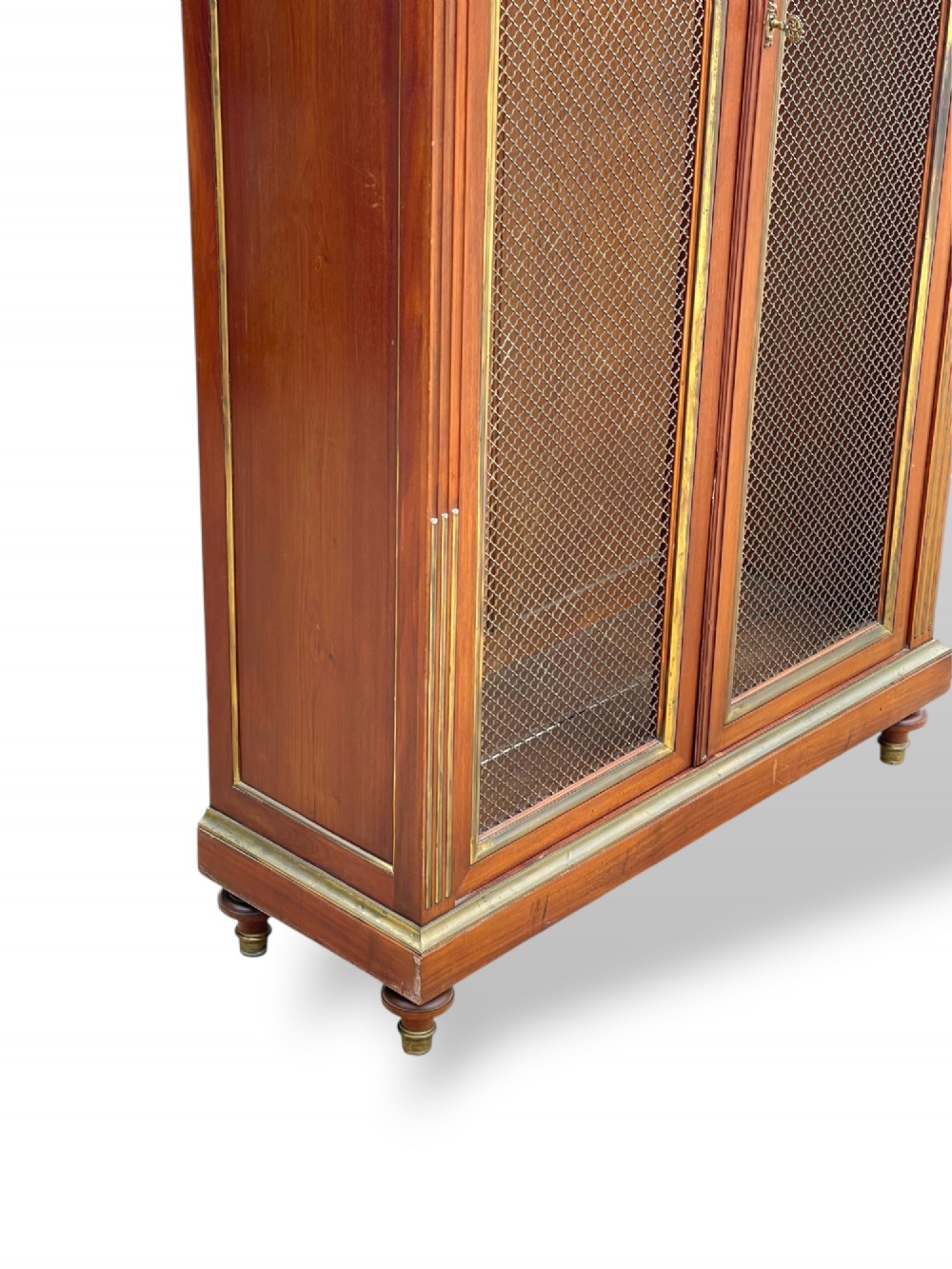 A tall French Empire style mahogany two-door bookcase featuring brass wire mesh door panels and fluted side columns. View X