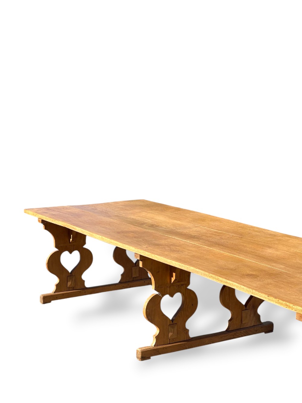 A large 19th-century English oak low coffee table featuring a three-plank top and trestle legs with heart-shaped cutouts connected by a central stretcher. View IV
