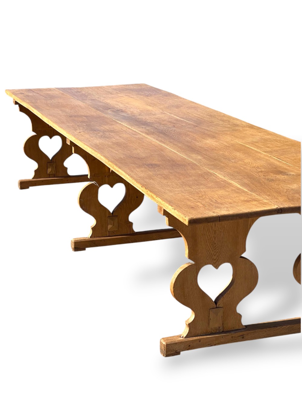 A large 19th-century English oak low coffee table featuring a three-plank top and trestle legs with heart-shaped cutouts connected by a central stretcher. View VI