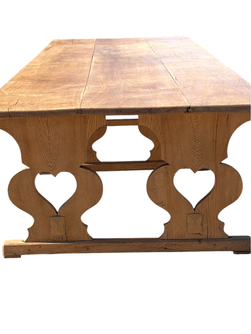 A large 19th-century English oak low coffee table featuring a three-plank top and trestle legs with heart-shaped cutouts connected by a central stretcher. View VII