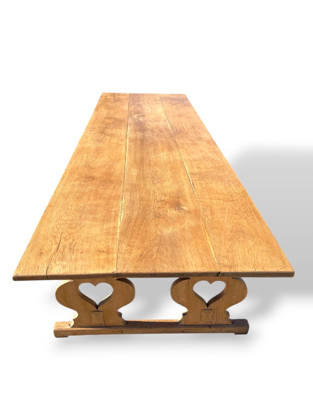 A large 19th-century English oak low coffee table featuring a three-plank top and trestle legs with heart-shaped cutouts connected by a central stretcher. View IX