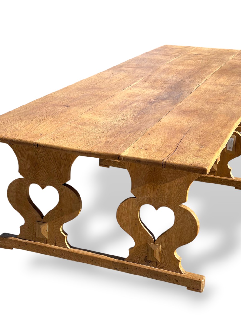A large 19th-century English oak low coffee table featuring a three-plank top and trestle legs with heart-shaped cutouts connected by a central stretcher. View X