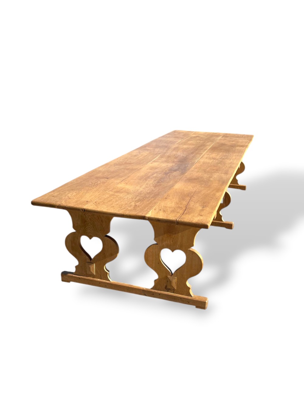 A large 19th-century English oak low coffee table featuring a three-plank top and trestle legs with heart-shaped cutouts connected by a central stretcher. View XI