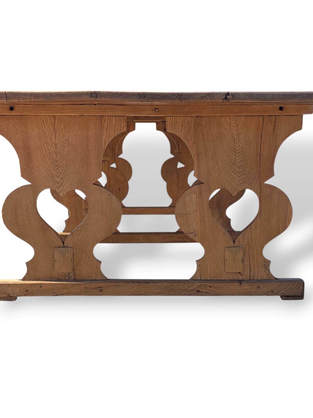 A large 19th-century English oak low coffee table featuring a three-plank top and trestle legs with heart-shaped cutouts connected by a central stretcher. View XII