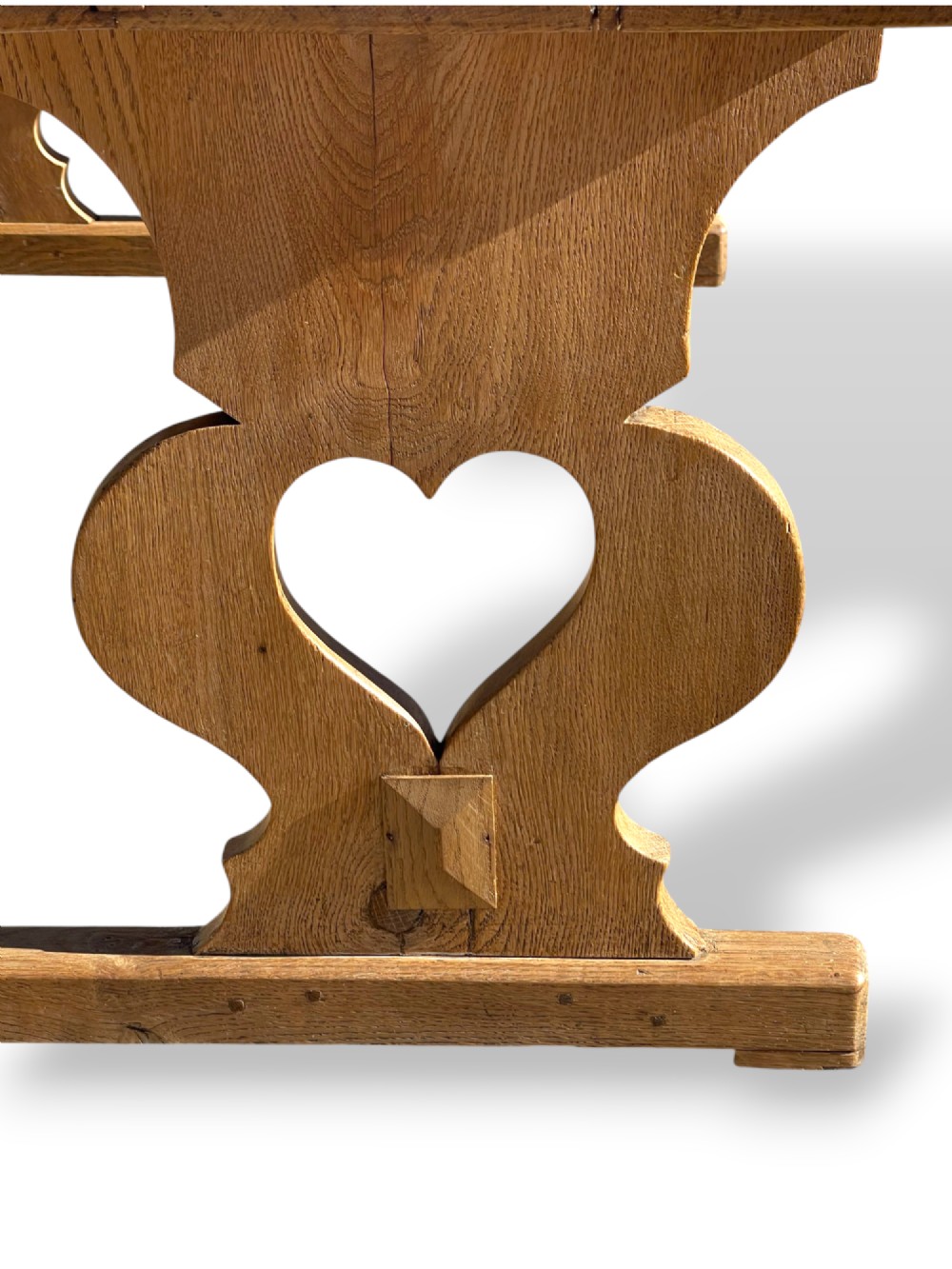 A large 19th-century English oak low coffee table featuring a three-plank top and trestle legs with heart-shaped cutouts connected by a central stretcher. View XV