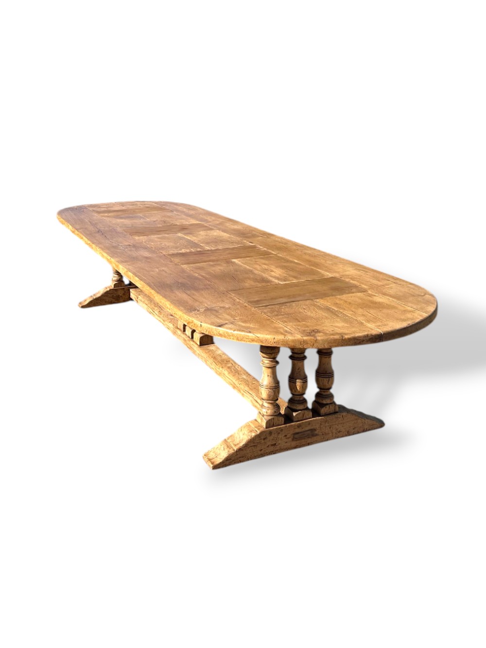 A four-metre French oak refectory dining table with rounded ends, a panelled timber top, and turned baluster legs set on trestle bases. View III