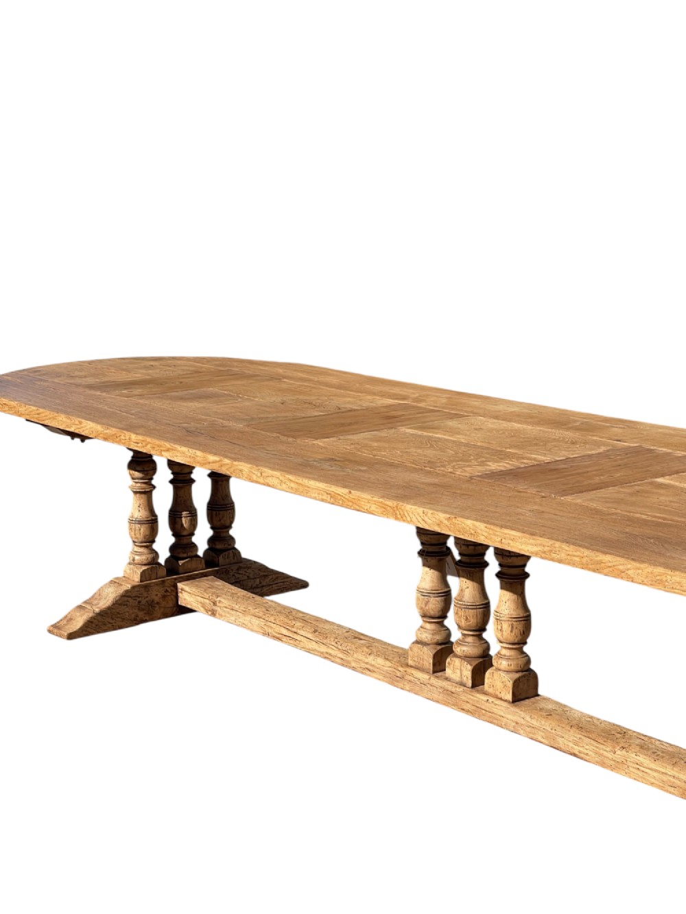 A four-metre French oak refectory dining table with rounded ends, a panelled timber top, and turned baluster legs set on trestle bases. View IV
