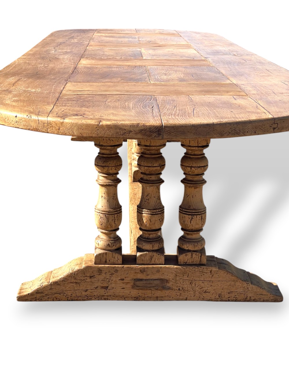 A four-metre French oak refectory dining table with rounded ends, a panelled timber top, and turned baluster legs set on trestle bases. View VII