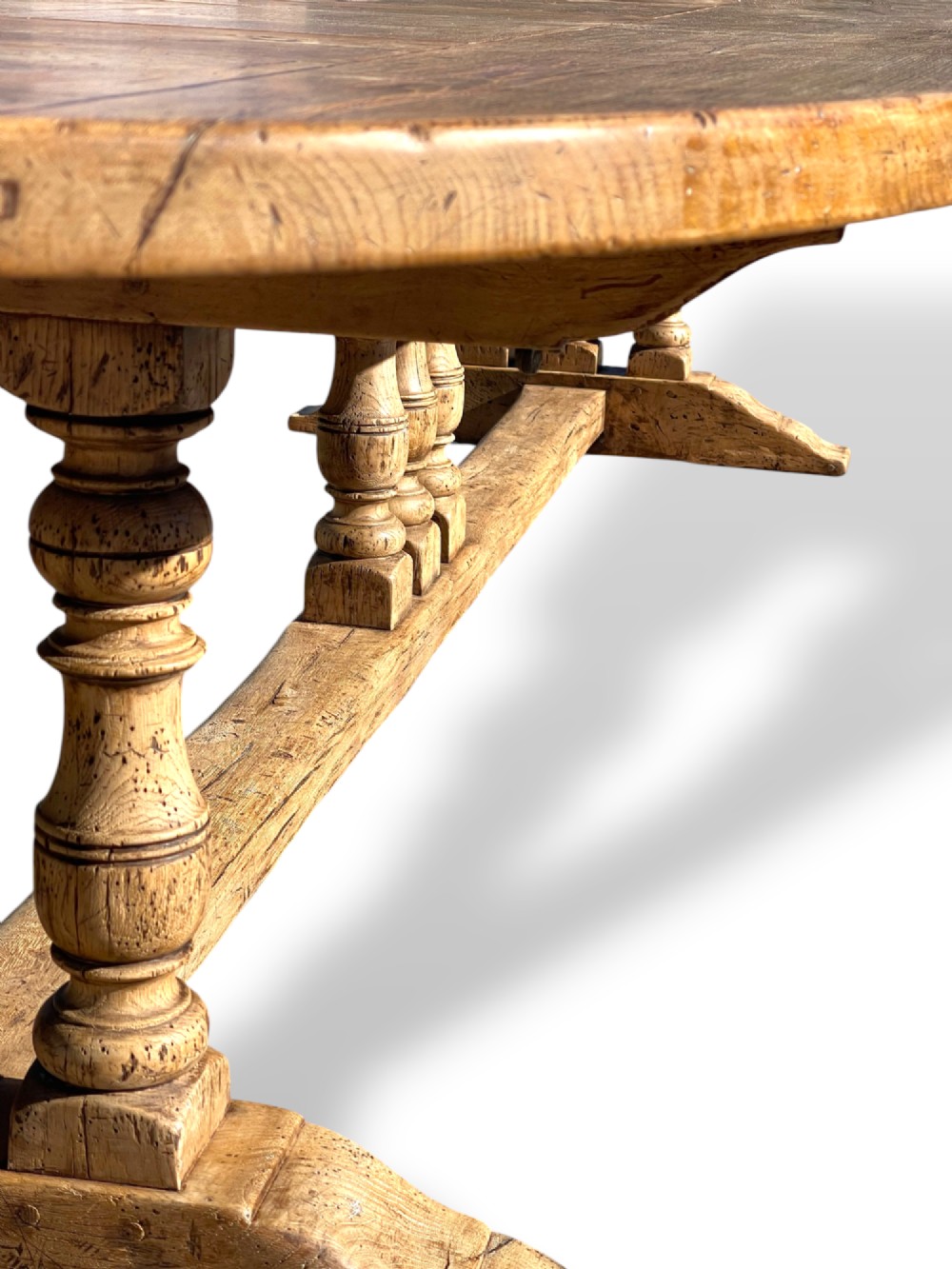 A four-metre French oak refectory dining table with rounded ends, a panelled timber top, and turned baluster legs set on trestle bases. View XII