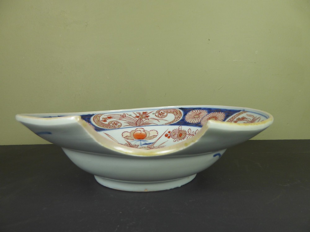An 18th-century Imari porcelain shaving bowl decorated with hand-painted blue and iron-red floral motifs, featuring a crescent cut-out along the rim. View II