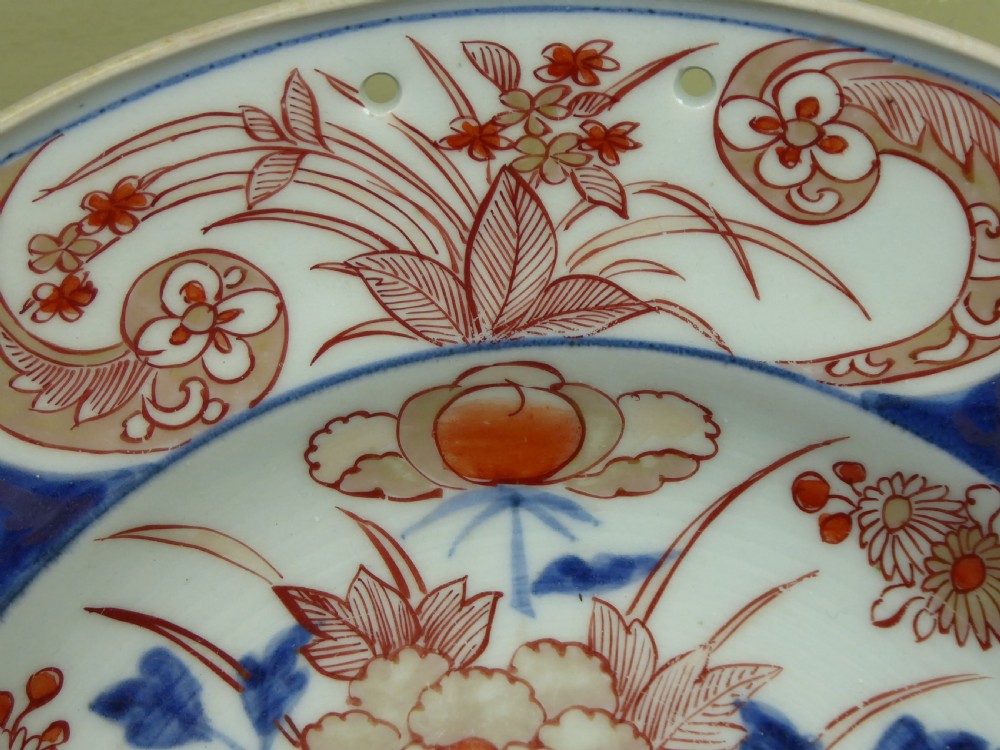 An 18th-century Imari porcelain shaving bowl decorated with hand-painted blue and iron-red floral motifs, featuring a crescent cut-out along the rim. View VI