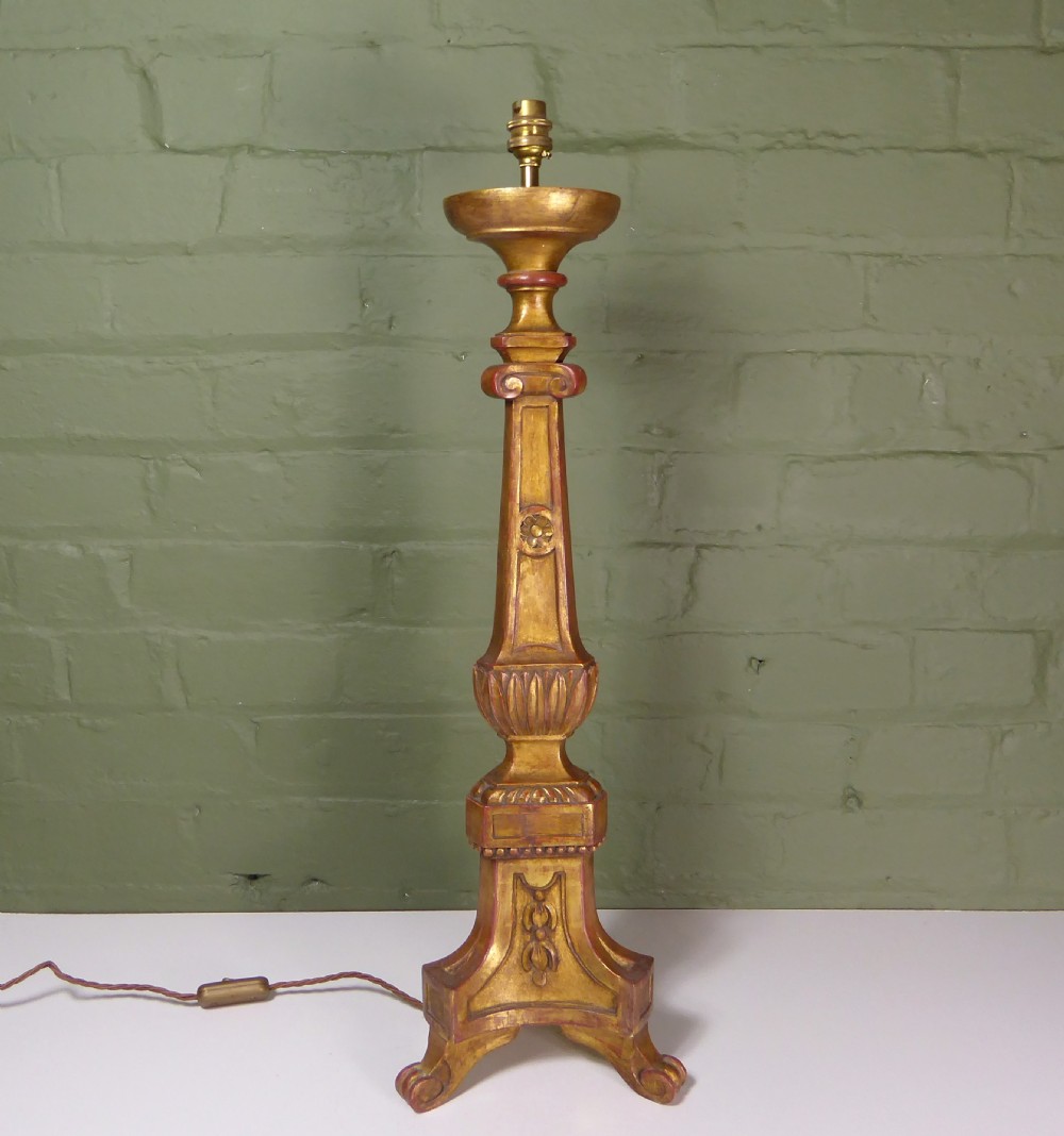 A tall 19th-century carved giltwood pricket candlestick converted into a table lamp base with a brass electrical fitting.