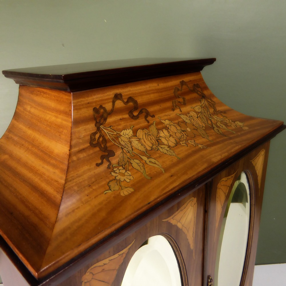 A 19th-century wooden tabletop cabinet featuring oval mirrored double doors, brass handles, brass ball feet, and floral marquetry inlay. View V