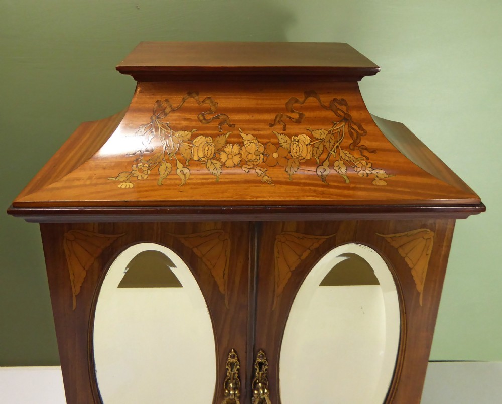 A 19th-century wooden tabletop cabinet featuring oval mirrored double doors, brass handles, brass ball feet, and floral marquetry inlay. View VIII