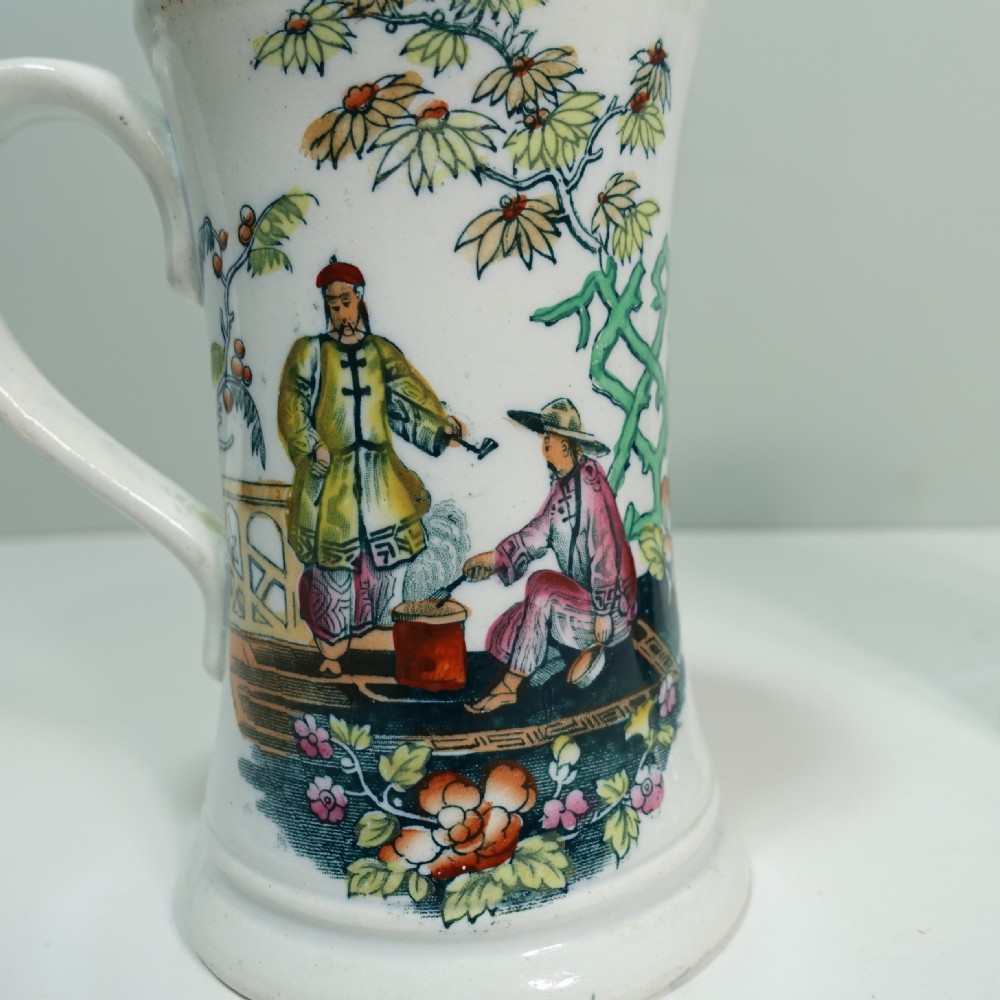 A pair of 19th-century white ceramic tankards decorated with hand-coloured Chinoiserie transfers of figures in a garden setting. View III