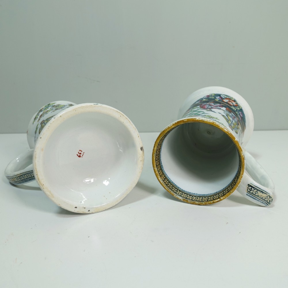 A pair of 19th-century white ceramic tankards decorated with hand-coloured Chinoiserie transfers of figures in a garden setting. View V